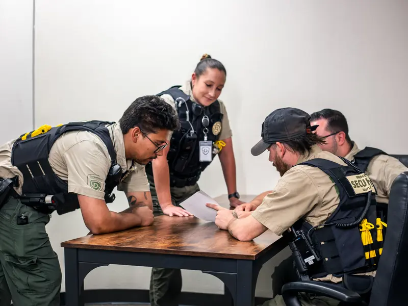 Security officers planning a shift assignment around a table