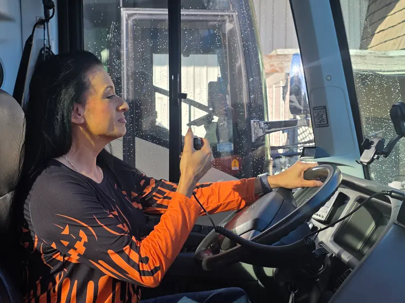 Bus driver talking on a HearClear speaker mic behind the wheel