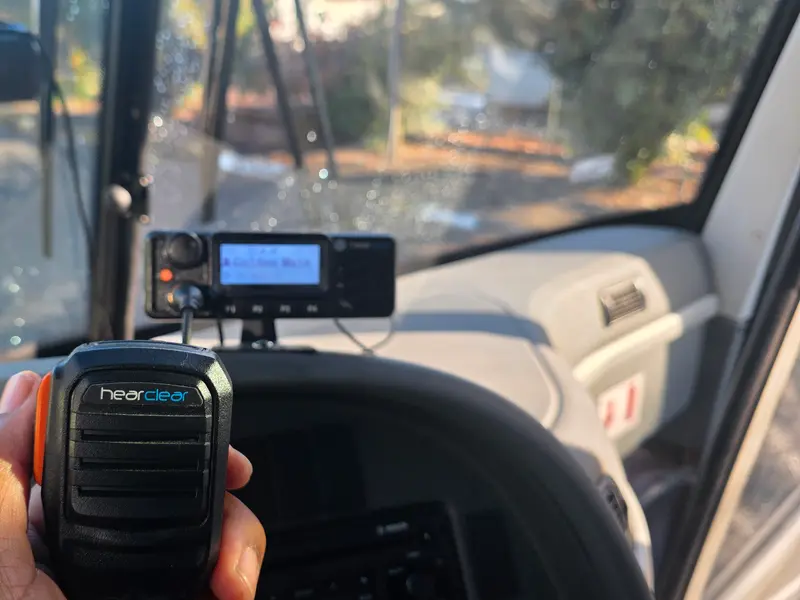 HearClear speaker mic in hand with the mobile radio on the dash